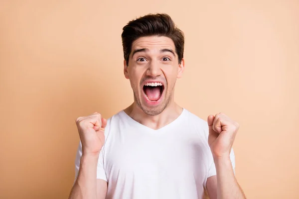 Foto de joven triunfante emocionado gritar feliz ganar levantar los puños aislados sobre fondo de color beige pastel —  Fotos de Stock