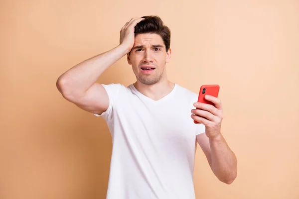 Foto di confuso giovane ragazzo tenere il braccio sulla testa sullen faccia stupore cattive notizie isolate su sfondo di colore beige — Foto Stock