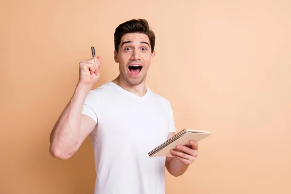 Portret van verbaasd grappige man open mond volledige test hold pen geïsoleerd op beige kleur achtergrond — Stockfoto