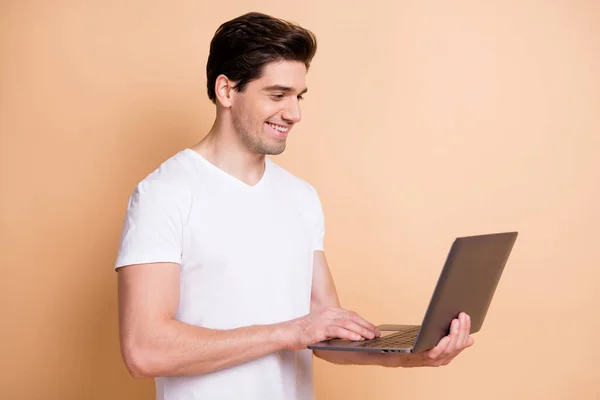 Retrato de chico alegre medio convertido guapo usando netbook escribir mensaje aislado sobre fondo de color beige — Foto de Stock