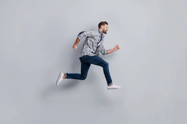 Longitud completa cuerpo tamaño lado perfil foto de hombre saltando corriendo rápido en ropa casual aislado gris color fondo —  Fotos de Stock