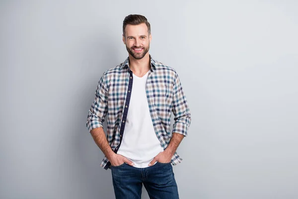 Retrato de atraente alegre conteúdo cara de mãos dadas em bolsos desgaste verificado camisa isolada sobre fundo cor pastel cinza — Fotografia de Stock