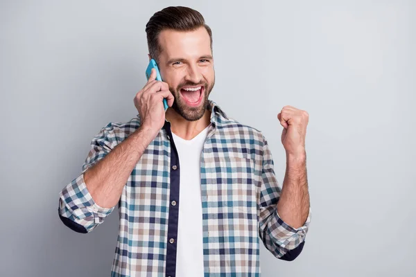 Φωτογραφία πορτρέτο του νεαρού άνδρα μιλώντας στο smartphone gesturing σαν νικητής χαμογελώντας απομονωμένο σε γκρι φόντο χρώμα — Φωτογραφία Αρχείου