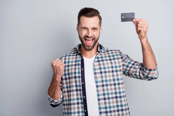 Foto portret van vrolijke man tonen bankkaart gebaren als loterij winnaar geïsoleerd op grijze achtergrond — Stockfoto