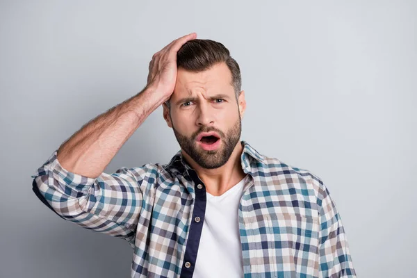 Foto de joven guapo conmocionado infeliz estresado hombre cometió un error sostener la cabeza de la mano aislado sobre fondo de color gris —  Fotos de Stock