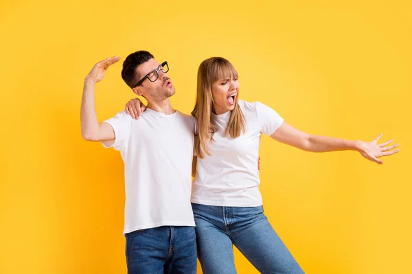 Foto de encantador bonita duas pessoas vestidas branco t-shirt óculos dançando isolado cor amarela fundo — Fotografia de Stock