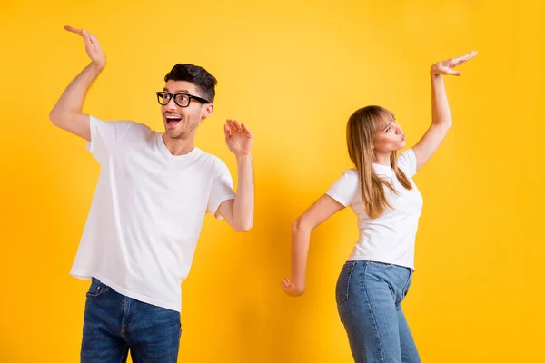 Foto de adorável casal jovem funky desgaste branco t-shirt óculos dançando isolado cor amarela fundo — Fotografia de Stock