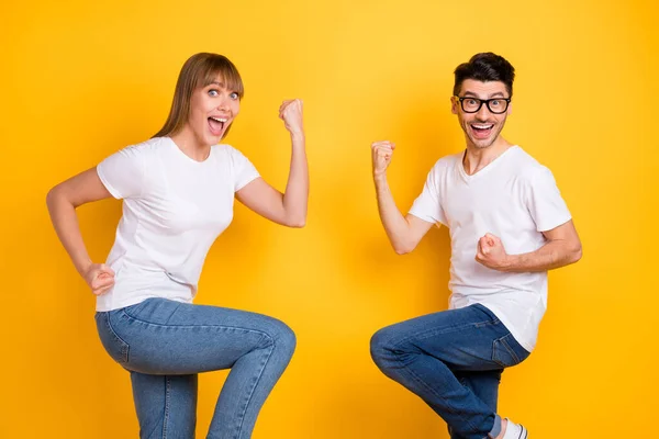 Foto de doce sorte duas pessoas vestidas branco t-shirt óculos levantando punhos isolado cor amarela fundo — Fotografia de Stock