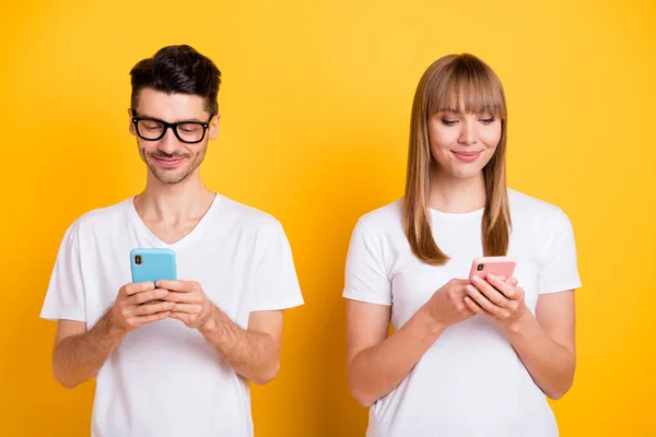 Foto van geïnteresseerd mooi jong stel dragen witte t-shirt bril chatten moderne gadgets geïsoleerde gele kleur achtergrond — Stockfoto