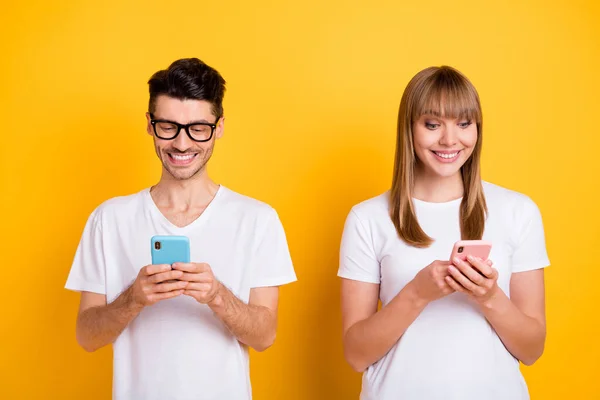 Foto de lindo encantador dos personas vestidas de blanco gafas de camiseta escribiendo dispositivos modernos aislados de color amarillo de fondo — Foto de Stock