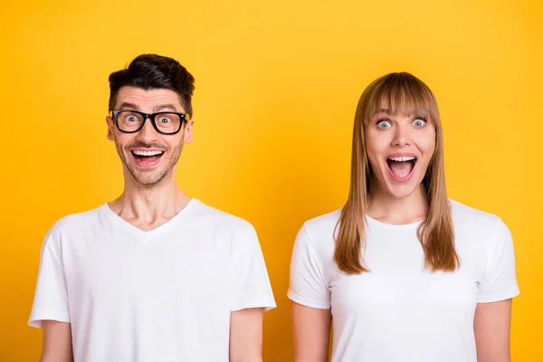 Fotografie šokované legrační dva lidé oblečené bílé tričko brýle otevřené ústa izolované žlutá barva pozadí — Stock fotografie