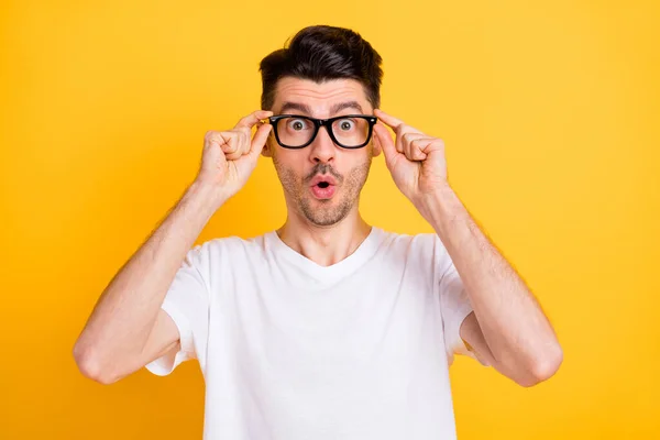 Foto von beeindruckt lustige junge Mann tragen weißes T-Shirt Arme Brille große Augen isoliert gelbe Farbe Hintergrund — Stockfoto