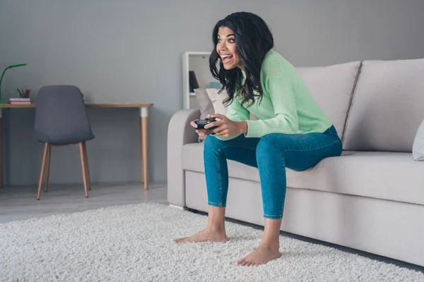 Profilo completo del corpo lato foto di giovane eccitata ragazza nera felice sorriso giocare video gioco joystick console sedersi divano a casa — Foto Stock