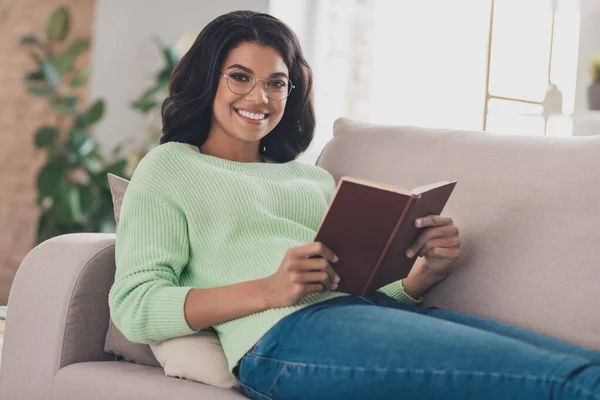 Foto de mujer afro americana atractiva feliz cama sofá leer libro novela usar gafas en el interior de la casa sala de estar — Foto de Stock