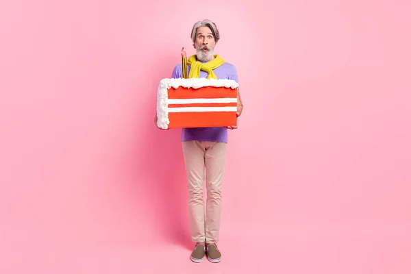 Bild av mogen man förvånad hålla stora skiva tårta födelsedag bunden tröja isolerad över pastell färg bakgrund — Stockfoto