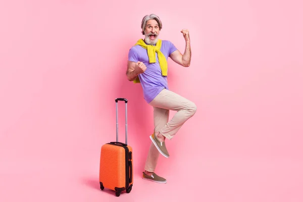 Foto do homem idoso feliz alegrar-se ganhar viagem de bagagem vitória férias ar voar camisola amarrada isolado sobre cor rosa fundo — Fotografia de Stock