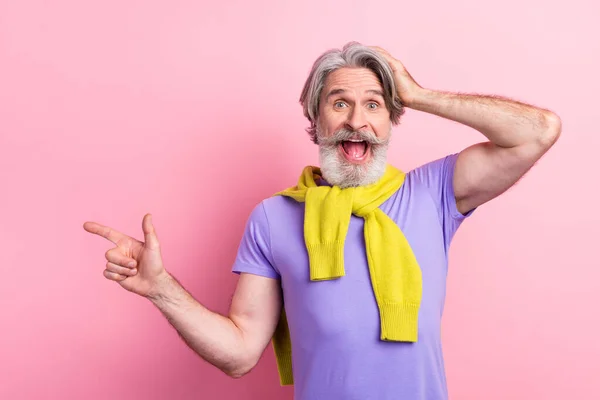 Retrato de atraente espantado alegre homem de cabelos grisalhos demonstrando cópia oferta de espaço isolado no fundo cor pastel rosa — Fotografia de Stock