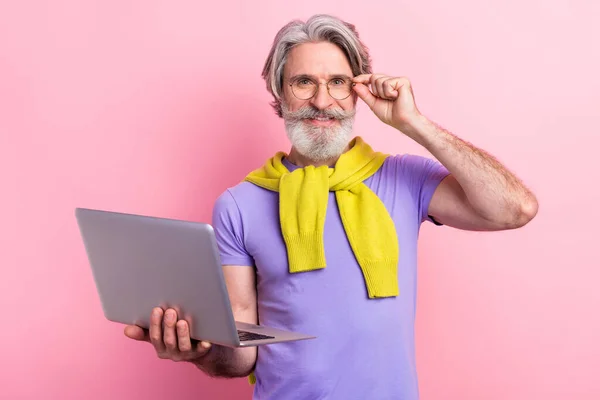 Retrato de atraente alegre hábil homem de cabelos grisalhos segurando na palma da mão usando laptop tocando especificações isoladas no fundo cor pastel rosa — Fotografia de Stock