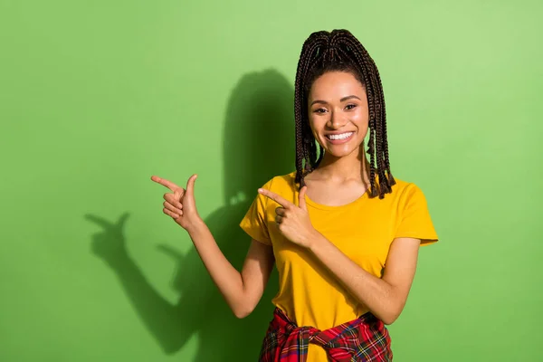 Foto von charmanten süßen dunklen Haut Frau tragen gelbes T-Shirt zeigt mit den Fingern leeren Raum isoliert grüne Farbe Hintergrund — Stockfoto