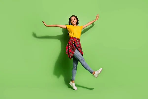 Foto de longitud completa de bastante dulce de piel oscura dama vestida camiseta amarilla bailando manos brazos lados aislados color verde fondo — Foto de Stock