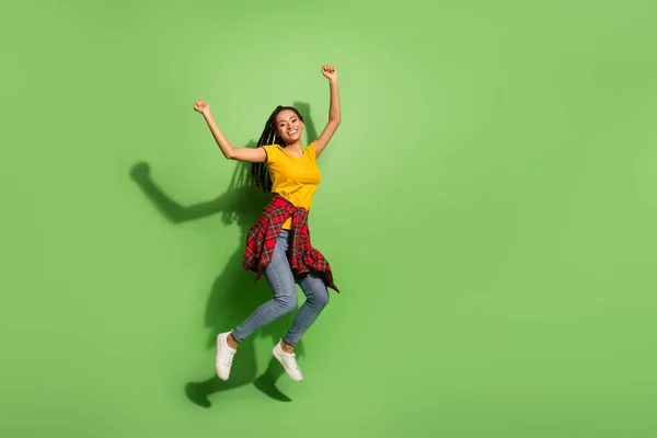 Full length photo of funny sweet dark skin woman wear yellow t-shirt jumping rising fists isolated green color background — Stock Photo, Image