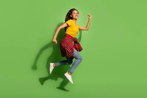 Foto de longitud completa de encantadora linda señora de piel oscura vestida camiseta amarilla saltando corriendo aislado fondo de color verde — Foto de Stock