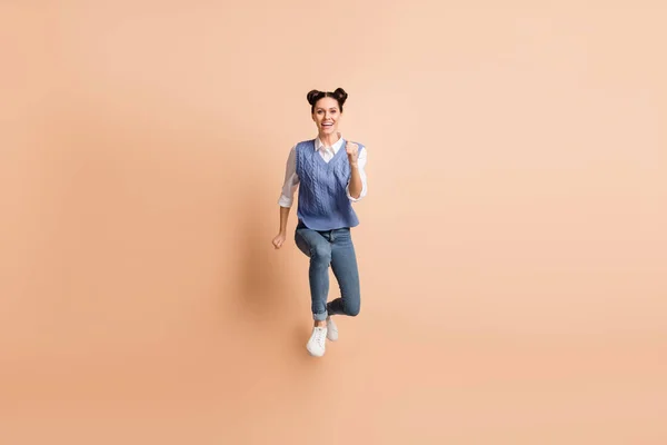 Volledige lengte foto van charmante mooie jonge meisje gekleed gebreide vest springen lopen geïsoleerde beige kleur achtergrond — Stockfoto