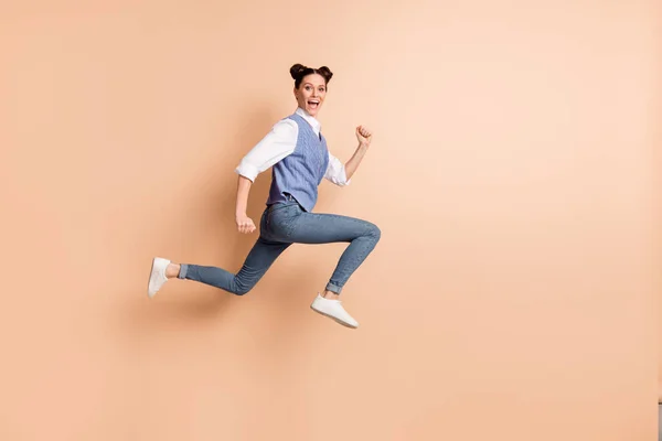 Foto de comprimento total de bonito adorável jovem senhora desgaste colete azul saltando alto correr rápido isolado cor bege fundo — Fotografia de Stock