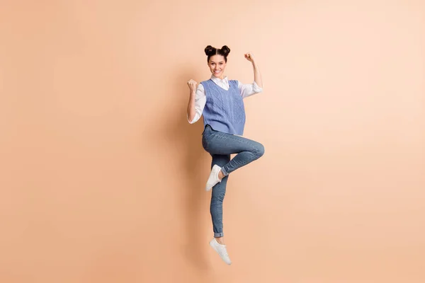 Volledige foto van charmante gelukkige jonge dame dragen blauwe vest springen hoog stijgende vuisten geïsoleerde beige kleur achtergrond — Stockfoto
