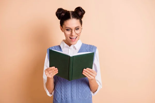 Foto de brilhante impressionado jovem senhora desgaste azul colete óculos lendo livro aberto isolado cor bege fundo — Fotografia de Stock