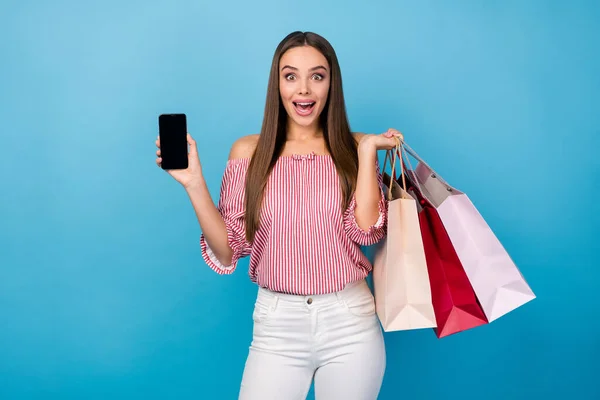 魅力的な明るい明るいストレートヘアの女の子の肖像画手の携帯電話で保持新しい服物事は、明るい青の色の背景に孤立 — ストック写真