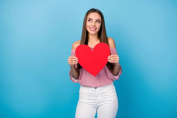 Portret van dromerig charmant vrolijk recht-harig meisje houden in handen hart denken geïsoleerd over helder blauwe kleur achtergrond — Stockfoto