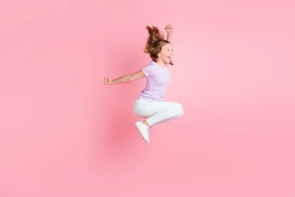 Full size profiel side photo of crazy amazed little girl jump up raise vuisten geïsoleerd op pastel roze kleur achtergrond — Stockfoto