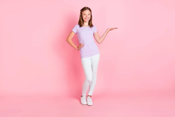 Full längd foto av glada glad liten flicka hålla händerna tomt utrymme midja annonsera isolerad på rosa färg bakgrund — Stockfoto