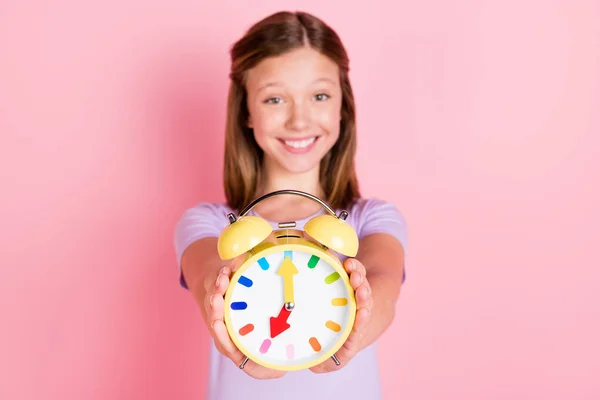 Foto de alegre bonito menina segurar despertador relógio mostrar-lhe tempo isolado no fundo cor-de-rosa pastel — Fotografia de Stock