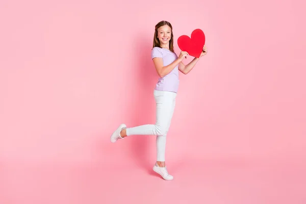 Foto de comprimento total da menina feliz segurar as mãos papel coração bom humor sorriso isolado na cor rosa fundo — Fotografia de Stock