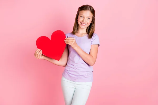 Foto de agradável adorável menina feliz segurar as mãos figura grande coração sorriso bom humor isolado no fundo cor-de-rosa — Fotografia de Stock