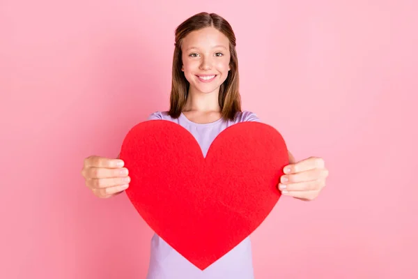 Foto de bonito positivo feliz menina dar-lhe grande forma do coração isolado no fundo cor-de-rosa pastel — Fotografia de Stock
