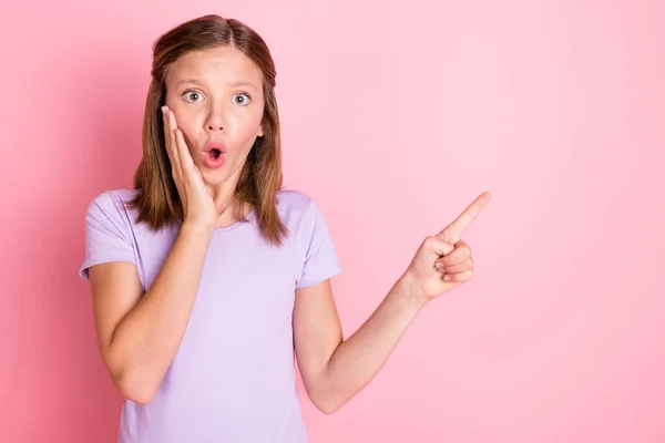 Foto di stupito scioccato piccola ragazza tenere mano zigomo punto dito vuoto spazio isolato su sfondo di colore rosa — Foto Stock