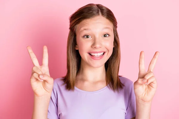 Foto de alegre bonito menina feliz fazer dedos v-sinais isolados no fundo cor-de-rosa pastel — Fotografia de Stock