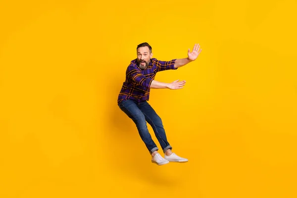 Full length body size photo of man jumping flying back while wind storm isolated on vibrant yellow color background — Zdjęcie stockowe