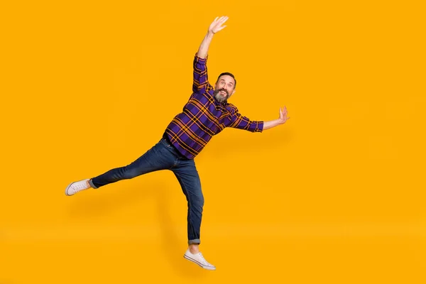 In voller Länge Foto von lustigen reifen Mann heben Hände Bein gute Laune isoliert auf Glanz helle gelbe Farbe Hintergrund — Stockfoto