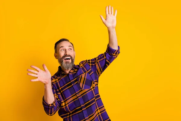 Портрет привлекательного мечтательного веселого парня, танцующего с весельем в клетчатой рубашке, изолированной на ярко-желтом фоне — стоковое фото