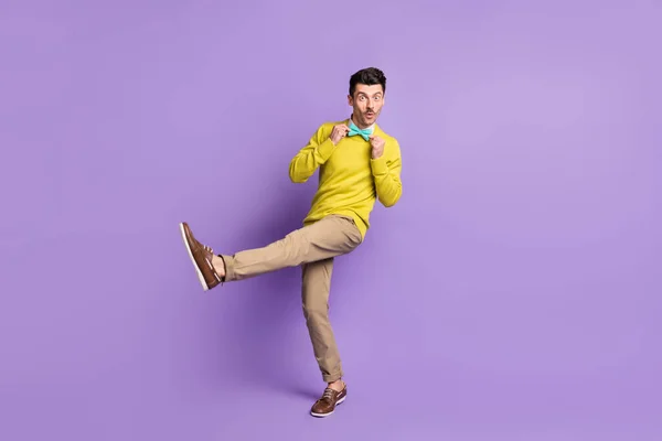 Full size Profilfoto von brünetten optimistischen Kerl Tanz tragen gelben Pullover Hose Turnschuhe isoliert auf fliederfarbenem Hintergrund — Stockfoto