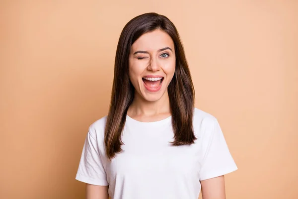 Foto portrét funky studentky mrkání blikání s úsměvem v bílém tričku izolované pastelové béžové barvy pozadí — Stock fotografie