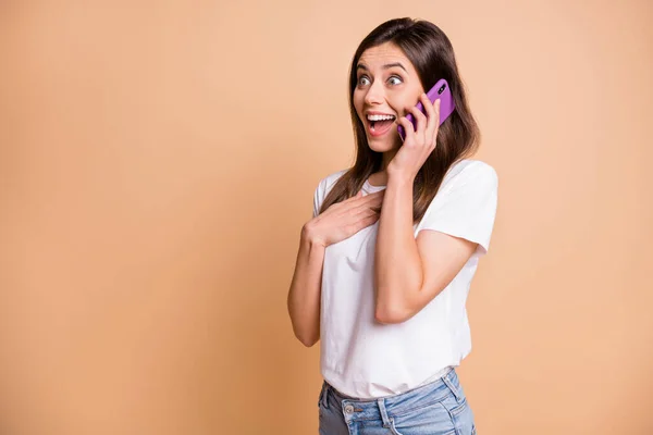 Foto portret van jonge vrouw praten op telefoon verbaasd hand op borst geïsoleerde pastel beige kleur achtergrond copyspace — Stockfoto