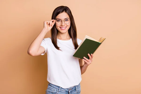 Foto retrato de niña con gafas sonriente libro de lectura estudiando en la universidad aislado pastel beige color fondo —  Fotos de Stock