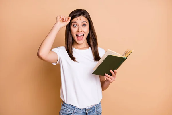 Foto retrato de estudante inteligente preparando-se para exames segurando livro olhando isolado pastel cor bege fundo — Fotografia de Stock