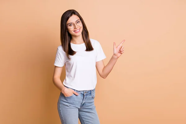 Foto porträtt av kvinnliga student i glasögon pekar finger tomt utrymme rekommendera isolerad pastell beige färg bakgrund — Stockfoto