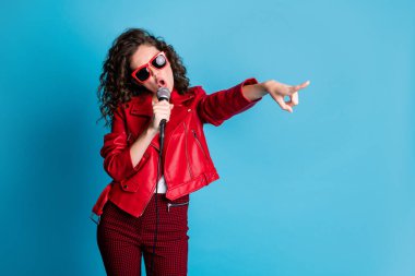 Portrait of attractive person open mouth singing hold mic idicate finger empty space isolated on blue color background clipart
